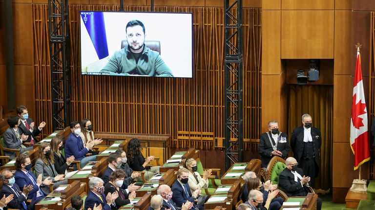 Members of parliament applaud as Ukrainian President Volodymyr Zelenskyy, who appears on a screen, addresses the Canadian parliament in Ottawa, Ontario, Canada, March 15, 2022. REUTERS/Christinne Muschi
