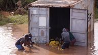 People loot a shipping container which was washed away after heavy rains caused flooding, in Durban, South Africa