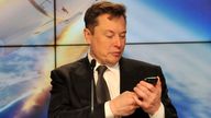SpaceX founder and chief engineer Elon Musk looks at his mobile phone during a post-launch news conference to discuss the SpaceX Crew Dragon a