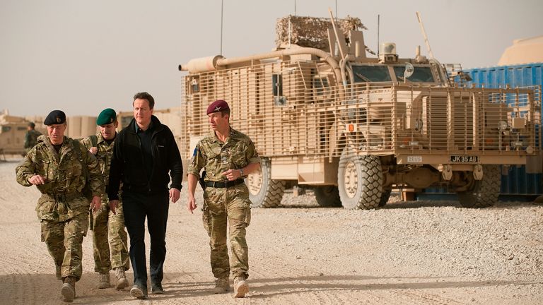 Britain's Prime Minister David Cameron (3rd L) walks past a Mastiff armored vehicle as he drives through Patrol Base 2 between Lashkar Gah and Gereshk December 6, 2010. Cameron, visiting Afghanistan on an unannounced trip, has said troops could start withdrawing from the country as early as next year.  Photograph taken December 6, 2010. REUTERS/ Leon Neal/Pool (AFGHANISTAN - Tags: POLITICS CONFLICT MILITARY)