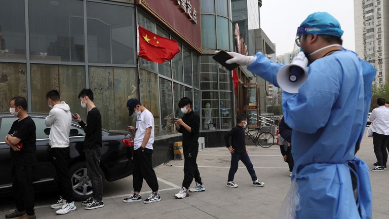 A worker guideS people as they line up to take a nucleic acid test at a mobile testing site following the coronavirus disease (COVID-19) outbreak, in Beijing, China April 11, 2022. REUTERS/Tingshu Wang
