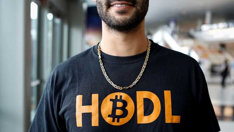A Bitcoiner wears a T-shirt that says &#39;HODL&#39; - encouraging people to hold on to their crypto. The slogan&#39;s inspired by a typo made on a Bitcoin forum years ago