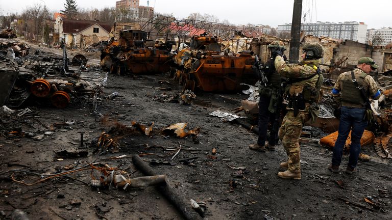 A serviceman uses his mobile phone to film a destroyed Russian tank and armoured vehicles, in Bucha, on 2 April