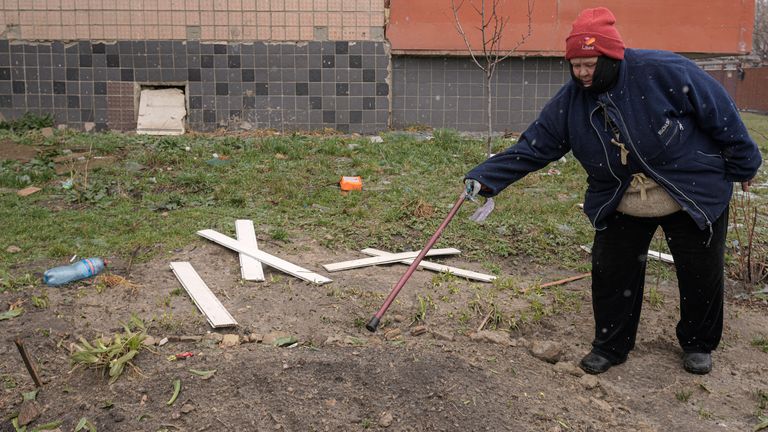 A woman points to a makeshift grave of a man killed by Russian forces, according to residents, and buried outside a building in Bucha. Pic AP