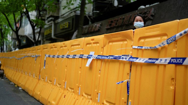 FILE PHOTO: A woman looks over a barrier at an area under lockdown amid the coronavirus disease (COVID-19) pandemic, in Shanghai, China April 13, 2022. REUTERS/Aly Song/File Photo
