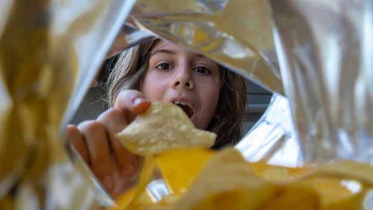 A boy eating crisps from a package. Pic: iStock 