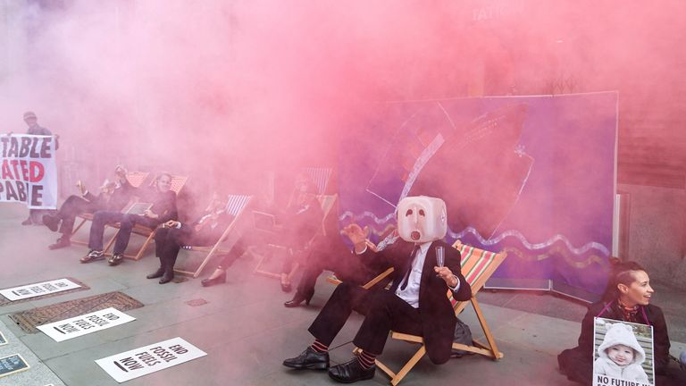 Pink smoke billows over members of Extinction Rebellion staging a protest against the use of and investment in fossil fuel, outside offices of Vanguard Asset Management on Earth Day in the City of London, Britain, April 22, 2022. REUTERS/Toby Melville
