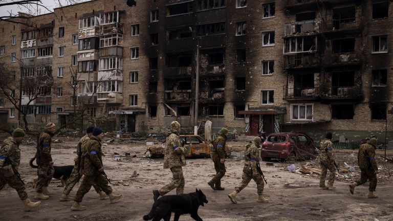 Ukraynalı askerler, 6 Nisan 2022 Çarşamba, Ukrayna, Kiev'in eteklerindeki Irpin'de ağır hasarlı konutların yanında yürüyor. (AP Photo/Felipe Dana) PIC:AP