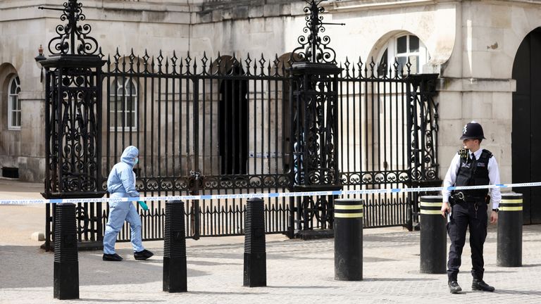 A police forensic official walks outside the Horse Guards building as a police officer stands guard at the cordoned-off area on Whitehall in Westminster after the road was closed by police following an incident involving the arrest of a man near Downing Street, in London, Britain, April 18, 2022. REUTERS/Henry Nicholls
