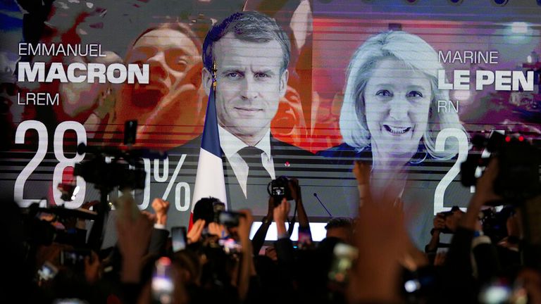 A screen shows French President Emmanuel Macron and far-right candidate Marine Le Pen at her election day headquarters in Paris