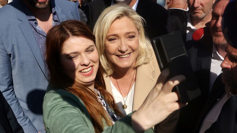 Marine Le Pen, French far-right National Rally (Rassemblement National) party candidate for the 2022 French presidential election, makes a selfie with a supporter as she visits a local market in Etaples on the last day of campaigning, ahead of the second round of the presidential election, France, April 22, 2022. REUTERS/Yves Herman
