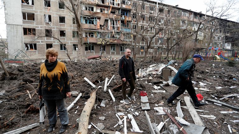 地元住民は、2022年4月18日、ウクライナの南部港湾都市マリウポリでのウクライナとロシアの紛争中にひどく損傷したアパートのグループの近くの中庭を歩きます。ロイター/アレクサンダーエルモシェンコ