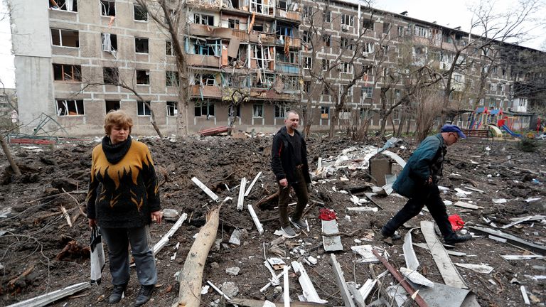 Local residents walk in a courtyard near a block of flats heavily damaged during Ukraine-Russia conflict in the southern port city of Mariupol, Ukraine April 18, 2022. REUTERS/Alexander Ermochenko
