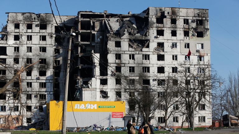 Yerel sakinler, 20 Nisan 2022, Ukrayna'nın güney liman kenti Mariupol'da Ukrayna-Rusya ihtilafı sırasında yıkılan bir apartmanın yanından geçiyorlar. REUTERS/Alexander Ermochenko