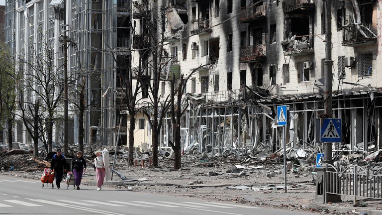 People walk along a street near a building damaged during Ukraine-Russia conflict in the southern port city of Mariupol, Ukraine April 25, 2022. REUTERS/Alexander Ermochenko
