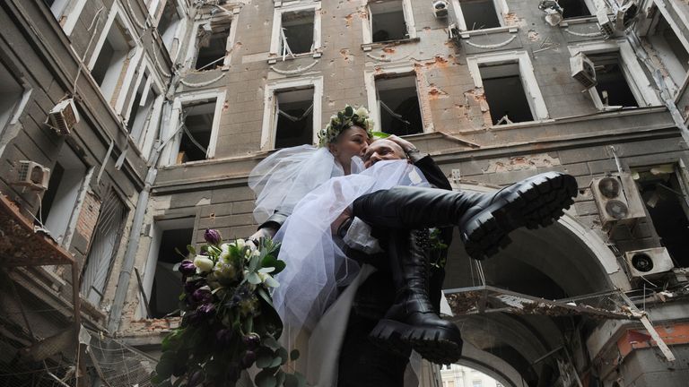 Volunteers Anastasia, left, and Anton pose for a picture in a yard of an apartment building destroyed by shelling during their wedding celebration in Kharkiv, Ukraine, Sunday, April 3, 2022. (AP Photo/Andrew Marienko)