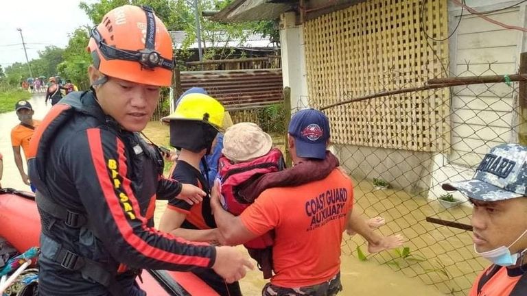 Rescue personnel assist a person onto a rescue boat along a flooded road, after the tropical storm Megi hit in Capiz Province, Philippines April 12, 2022. Philippine Coast Guard/Handout via REUTERS THIS IMAGE HAS BEEN SUPPLIED BY A THIRD PARTY. MANDATORY CREDIT. NO RESALES. NO ARCHIVES
