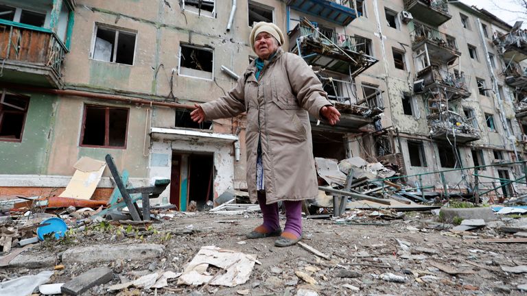 84 yaşındaki yerel sakin Raisa Budarina, 18 Nisan 2022'de Ukrayna'nın güney liman kenti Mariupol'da Ukrayna-Rusya ihtilafı sırasında ağır hasar gören bir apartman bloğunun dışında konuşurken tepki gösteriyor. REUTERS/Alexander Ermochenko