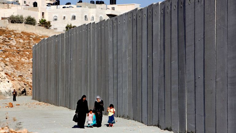 FILE PHOTO: A Palestinian family walk by a section of the controversial Israeli barrier in Shuafat refugee camp in the West Bank near Jerusalem September 22, 2009. U.S. President Barack Obama will broker his first summit of Israeli and Palestinian leaders on Tuesday but is given little chance of achieving a breakthrough toward relaunching long-stalled peace talks. REUTERS/Yannis Behrakis/File Photo (WEST BANK POLITICS)
