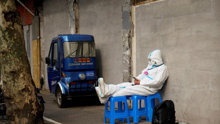 FILE PHOTO: A worker in a protective suit sits on plastic stools following the coronavirus disease (COVID-19) outbreak in Shanghai, China March 30, 2022. REUTERS/Aly Song/File Photo
