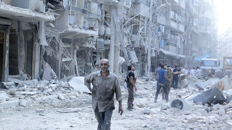 A man searches for survivors after a barrel bomb attack in Aleppo, 2015