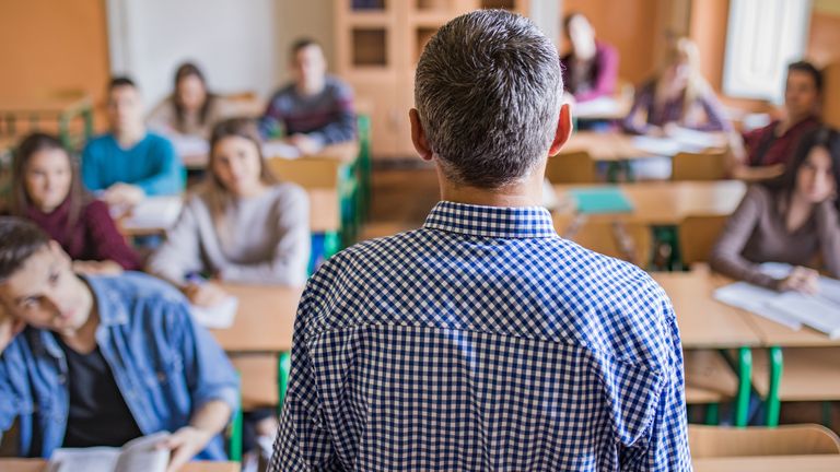 Back view of male professor giving lecture to high school students in the classroom. Pic: iStock