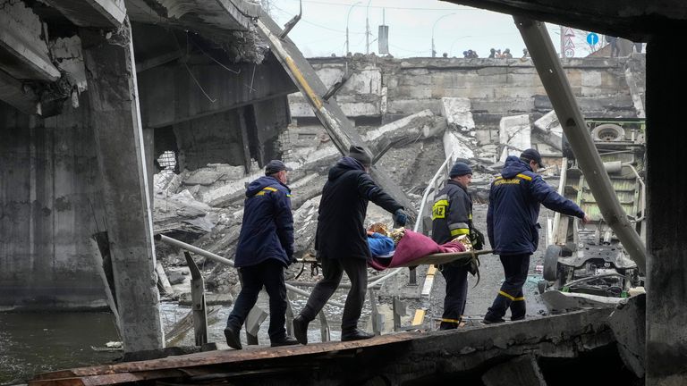 Ukrainian rescue workers carry an elderly woman under the destroyed bridge in Irpin close to Kyiv close to Kyiv, Ukraine, Friday, Apr. 1, 2022. The more than month-old war has killed thousands and driven more than 10 million Ukrainians from their homes including almost 4 million from their country. (AP Photo/Efrem Lukatsky)