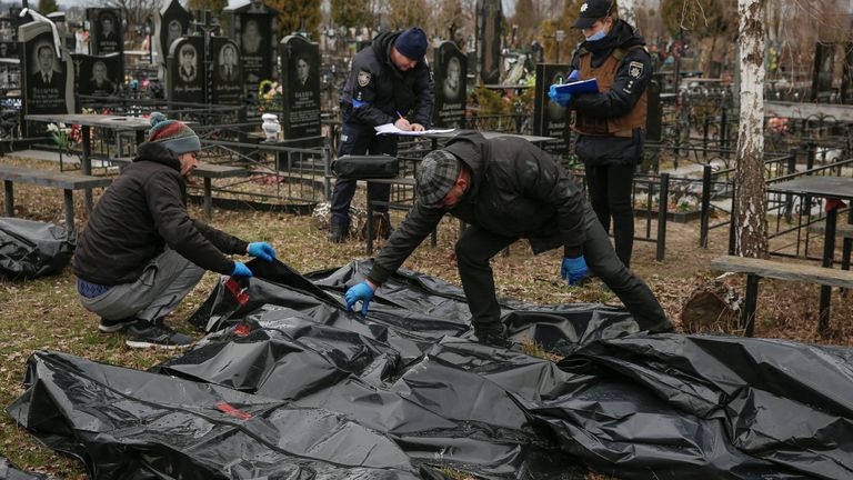 Funeral service employees and police investigators work with bodies of civilians, collected from streets to local cemetery, as Russia?s attack on Ukraine continues, in the town of Bucha, outside Kyiv, Ukraine April 6, 2022. REUTERS/Oleg Pereverzev
