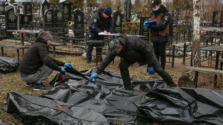 Funeral service employees and police investigators work with bodies of civilians, collected from streets to local cemetery, as Russia?s attack on Ukraine continues, in the town of Bucha, outside Kyiv, Ukraine April 6, 2022. REUTERS/Oleg Pereverzev
