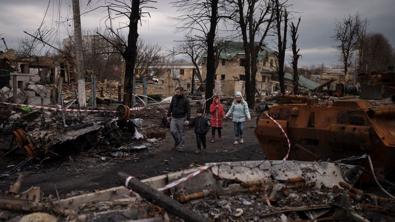 A family walks amid destroyed Russian tanks in Bucha, on the outskirts of Kyiv, Ukraine, Wednesday, April 6, 2022. (AP Photo/Felipe Dana)


