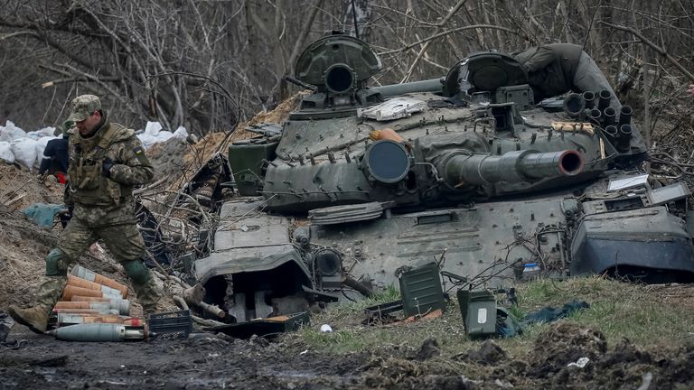 Ukraynalı bir asker, Rusya'nın Ukrayna'ya saldırısı devam ederken, Ukrayna'nın Kiev bölgesindeki Vablya köyünde terk edilmiş bir Rus tankının yanında yürüyor, 5 Nisan 2022. REUTERS/Gleb Garanich