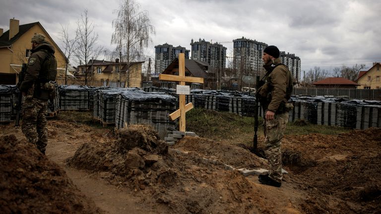 Ukraynalı askerler, sakinlerine göre Rusya'nın Ukrayna'yı işgali sırasında Rus askerleri tarafından öldürülen bir sivilin mezarının yanında duruyor, 6 Nisan 2022. REUTERS/Alkis Konstantinidis