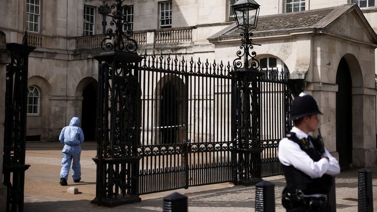 A police forensic official enters the Horse Guards building as a police officer stands guard at the cordoned-off area on Whitehall in Westminster after the road was closed by police following an incident involving the arrest of a man near Downing Street, in London, Britain, April 18, 2022. REUTERS/Henry Nicholls
