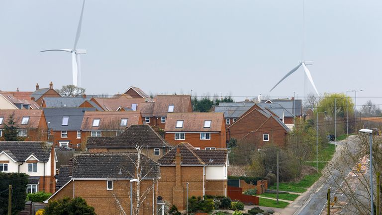 Wind turbines are seen behind houses in Burton Latimer, Britain, March 30, 2022. REUTERS/Andrew Boyers
