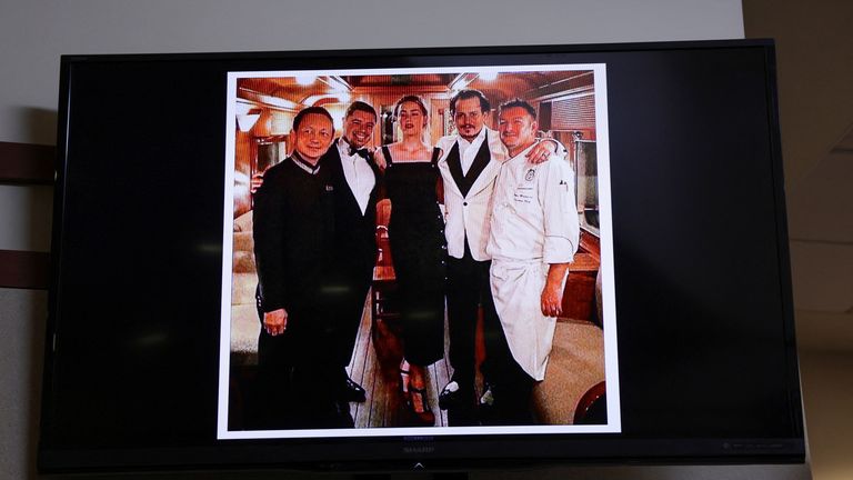     The photo presented as evidence of Depp and Heard with staff of the Orient Express taken at the end of their honeymoon trip in Singapore following their wedding in 2015, is seen on screen in Depp's defamation trial.