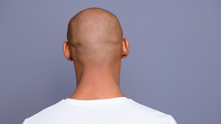 Close up back behind rear view photo dark skin he him his man turned to empty space distracted unrecognizable groomed shaved head wearing white t-shirt outfit clothes isolated on grey background