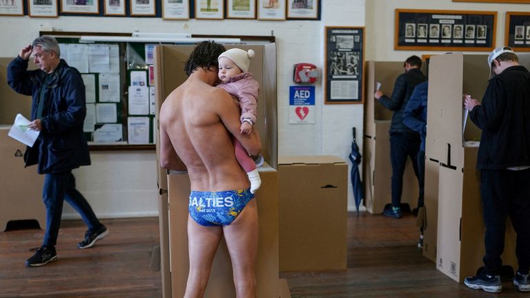 Local resident Jim Finn, holding 8-month old daughter Allegra Finn, casts his ballot on the morning of the national election at a Bondi Beach polling station in Sydney, Australia, May 21, 2022. REUTERS/Loren Elliott TPX IMAGES OF THE DAY