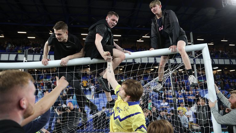Everton fans climb on the frame of the goal during a pitch invasion after the match to celebrate avoiding relegation from the Premier League