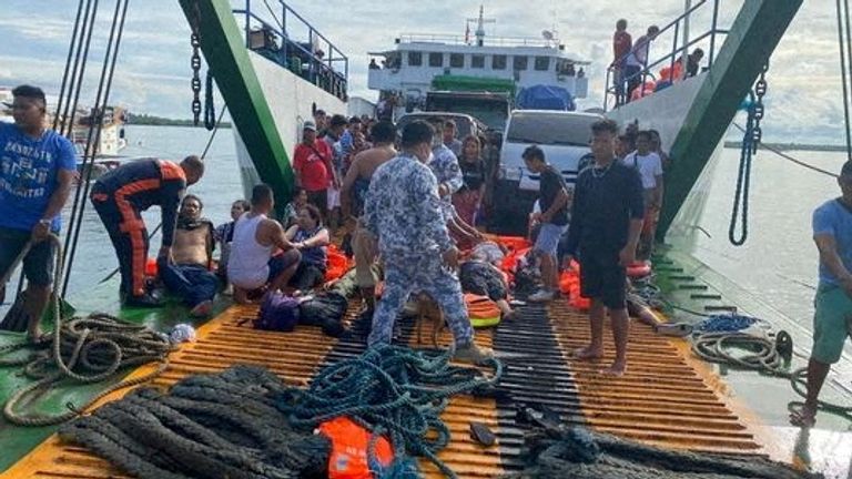 Philippine Coast Guard personnel assist rescued passengers after a vessel carrying more than 100 people caught fire near Real, Quezon province