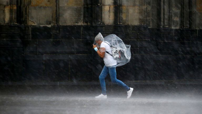 A person walks in a square in front of Cologne Cathedral during heavy rain in Cologne, Germany, May 19, 2022. REUTERS/Thilo Schmuelgen