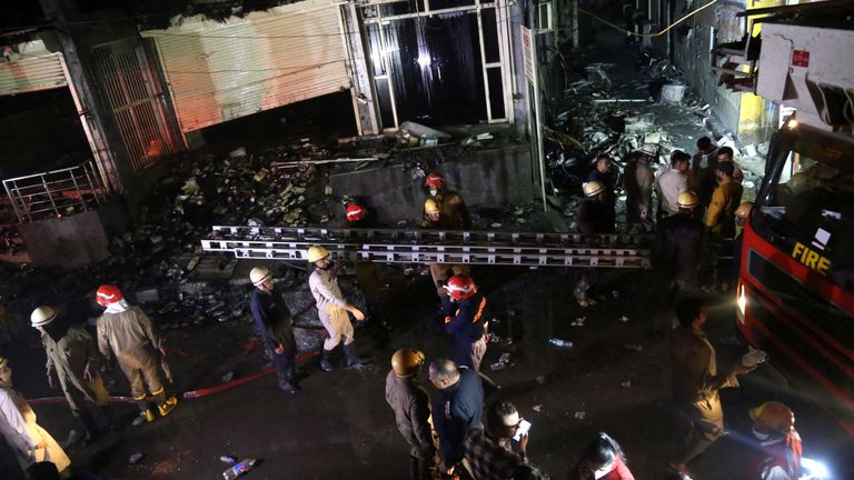 Fire fighters carry a ladder at the site a fire that broke out at a commercial building in Delhi&#39;s western suburb May 13, 2022. REUTERS/Stringer NO RESALES. NO ARCHIVES.
