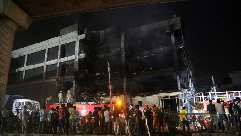 Rescue members and onlookers stand as fire fighters douse a fire that broke out at a commercial building in Delhi's western suburb May 13, 2022. REUTERS/Stringer NO RESALES. NO ARCHIVES.
