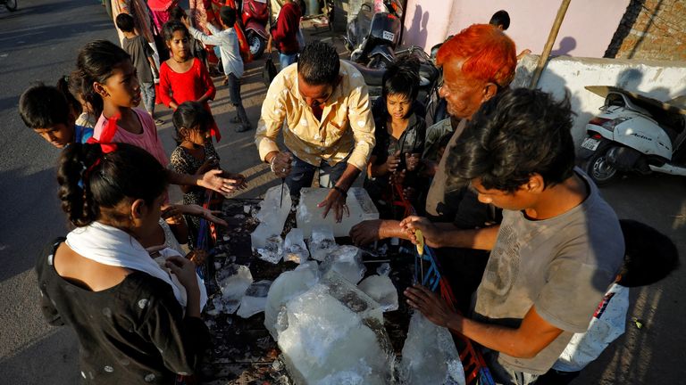 Um homem quebra um bloco de gelo para distribuir aos moradores de uma parte de Ahmedabad, na Índia.