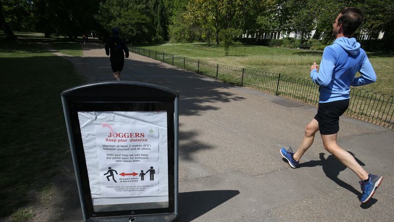 File photo dated 15/05/20 of a jogger running past a social distancing sign in Hyde Park in London during lockdown. A photo has been obtained by the Guardian showing Prime Minister Boris Johnson, his then-fiancee Carrie, and 17 other staff members in the Downing Street garden on May 15, 2020, with bottles of wine and a cheeseboard on a table in front of the Prime Minister. Issue date: Monday December 20, 2021.