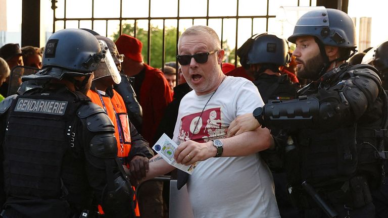 A fan is held by a police officer and a steward inside the Stade de France