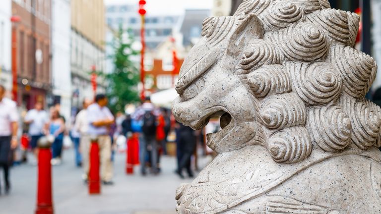 In the background is a guardian lion statue with London's crowded Chinatown