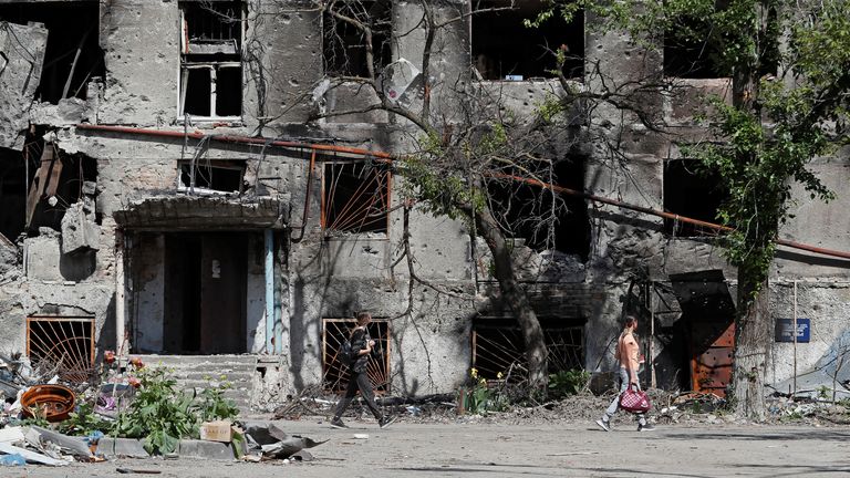 People walk past a residential building heavily damaged during Ukraine-Russia conflict in the southern port city of Mariupol, Ukraine May 30, 2022. REUTERS/Alexander Ermochenko