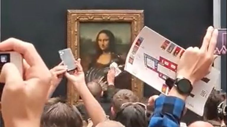 A staff member at the Louvre attempts to clean off cake smeared on glass protecting the Mona Lisa