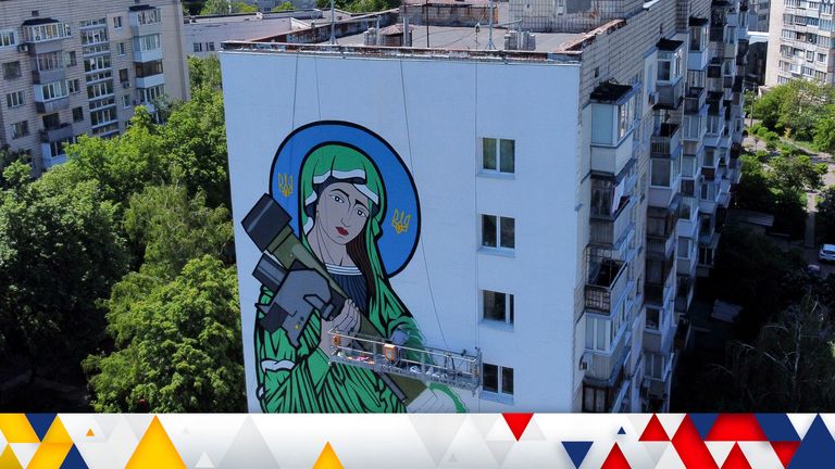 A worker paints a "Saint Javelin", a Virgin Mary holding an American-made anti-tank missile, in Kyiv, Ukraine, Tuesday, May 24, 2022. No matter where they live, the 3-month-old war never seems to be far away for Ukrainians. Those in towns and villages near the front lines hide in basements from constant shelling, struggling to survive with no electricity or gas ... and often no running water. But even in regions out of the range of the heavy guns, frequent air raid sirens wail as a constant reminder that a Russian missile can strike at any time ... even for those walking their dogs, riding their bicycles and taking their children to parks in cities like Kyiv, Kharkiv, Odesa and Lviv.(AP Photo/Natacha Pisarenko)