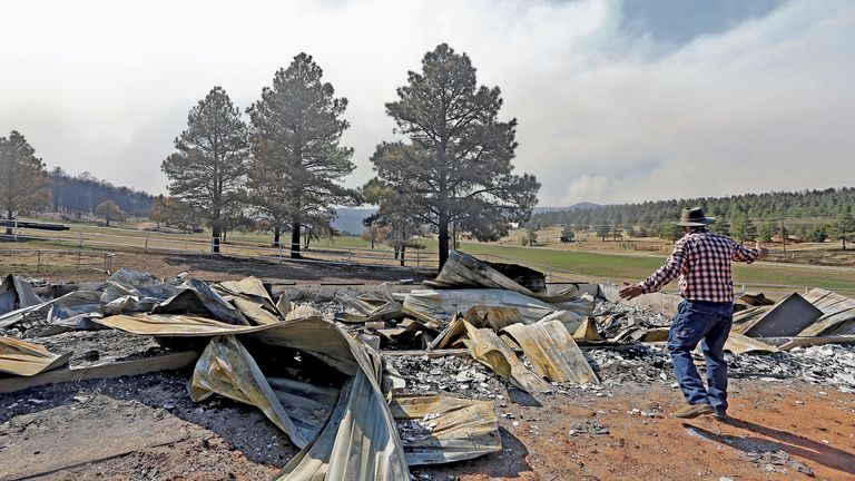 Jerry Gomez looks through the remains of his home following a wildfire in Rociada, New Mexico, on Tuesday, May 10, 2022. The largest wildfire burning in the United States was heading toward mountain resort towns in northern New Mexico on Wednesday, prompting officials to issue another set of warnings for more people to prepare to evacuate as the fast-moving fire picks up momentum. Gomez is enthusiastic about re-building. (Luis Sanchez Saturno/The New Mexican via AP) 